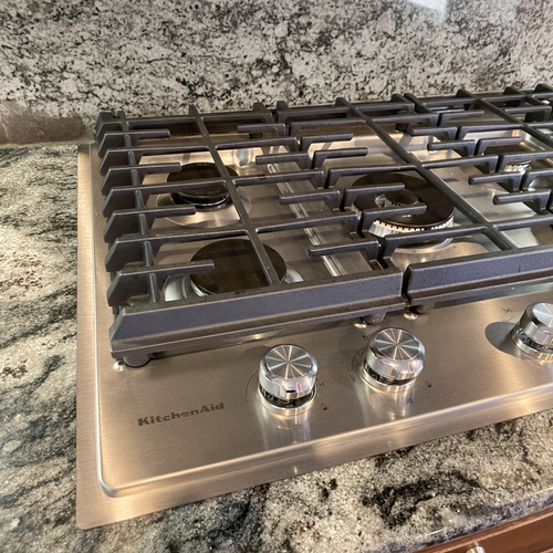 KitchenAid gas cooktop on granite countertop with a precision-fit stainless steel trim kit to cover gaps