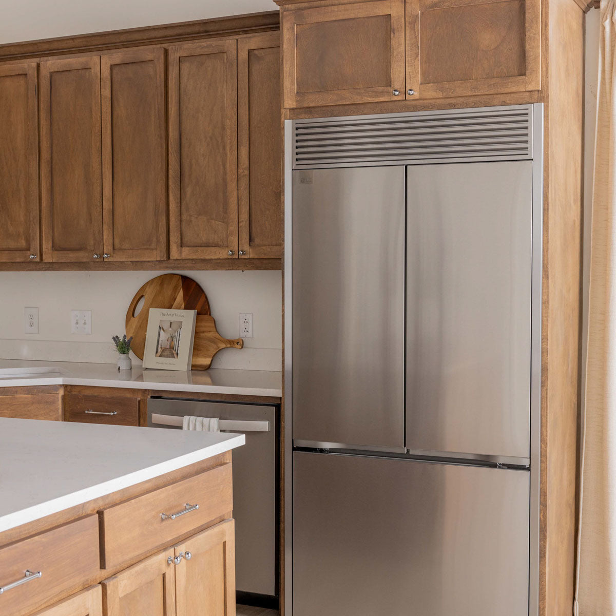 Modern kitchen highlighting a stainless steel refrigerator with customized trim kit for seamless finish