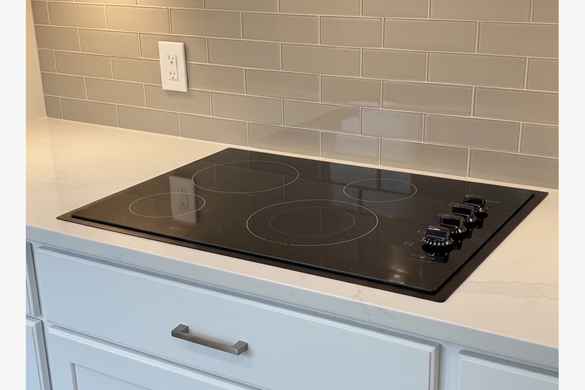 Electric stovetop with a custom matte black trim kit installed in a modern kitchen with cream subway tiles