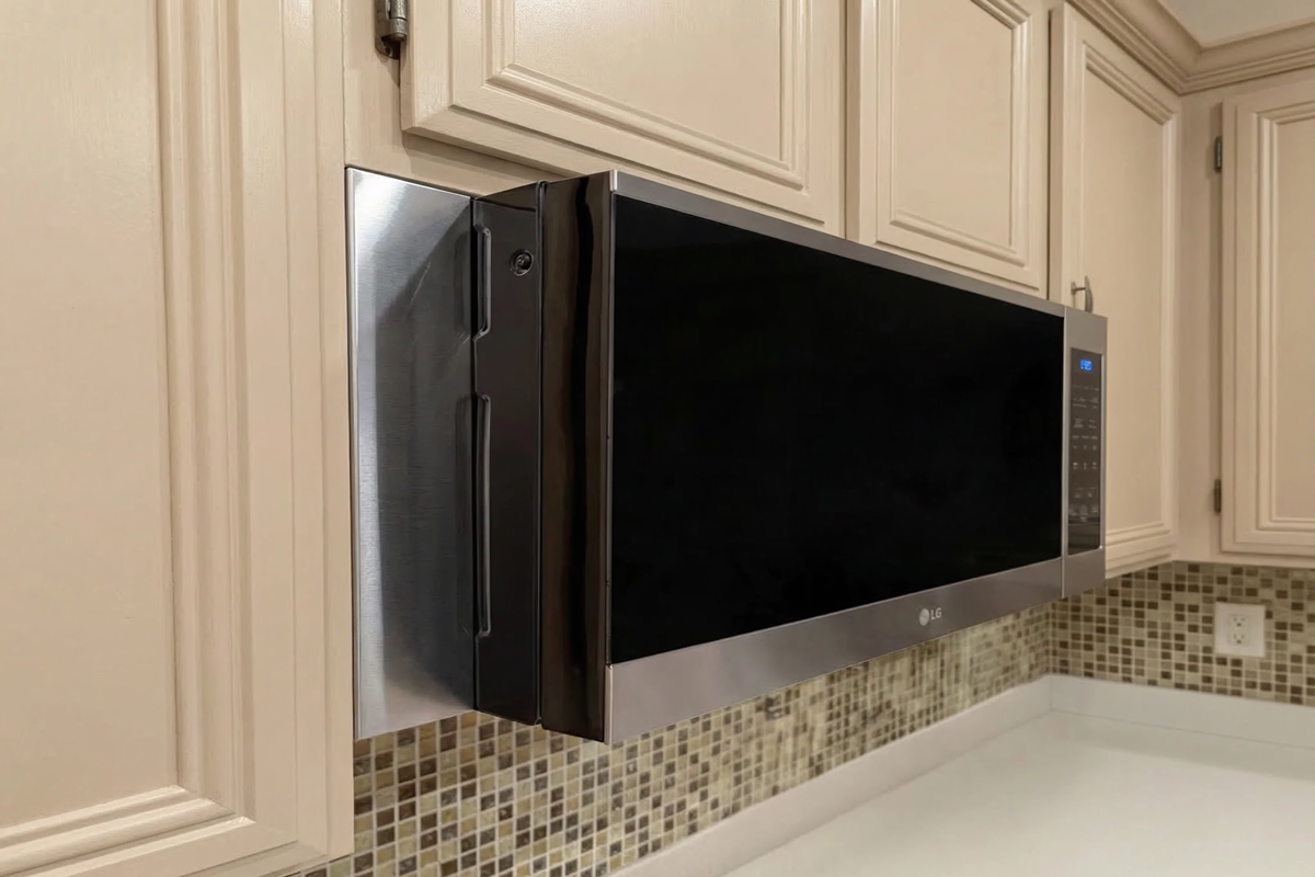 Side view of an LG over-the-range microwave with custom stainless steel filler panels covering the cabinet gap