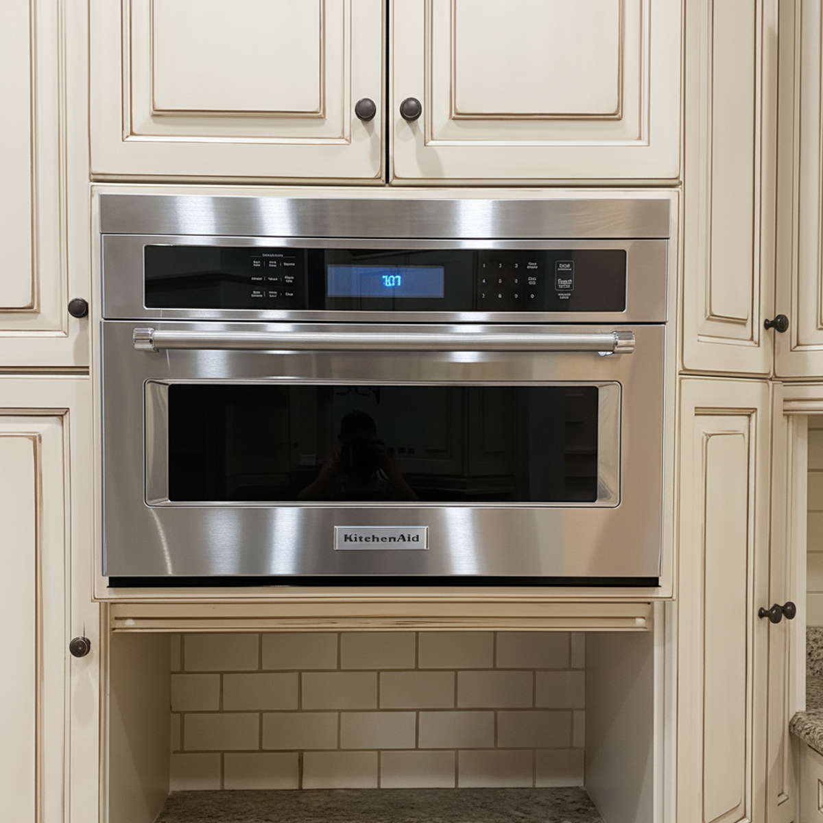 KitchenAid wall oven in beige cabinetry featuring custom-fit stainless steel filler strip to cover installation gaps for seamless finish