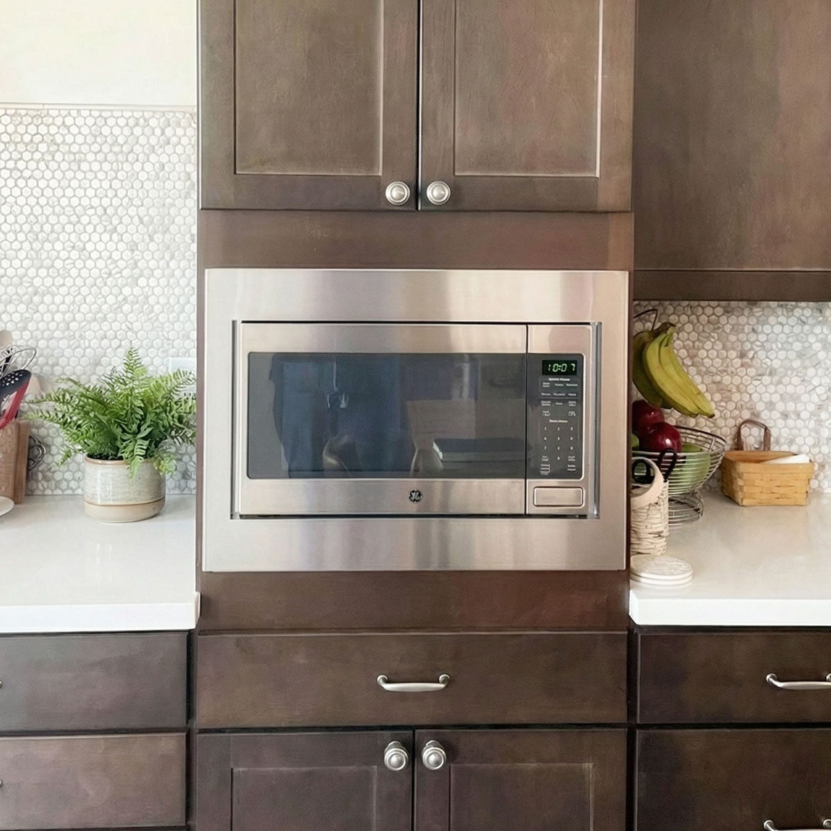 GE microwave installed with custom-made stainless steel trim kit in dark modern kitchen cabinetry
