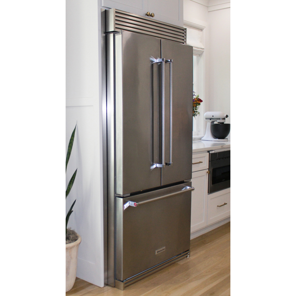 Side view of a KitchenAid French Door refrigerator featuring custom-fit stainless steel side panels and a top ventilation grille