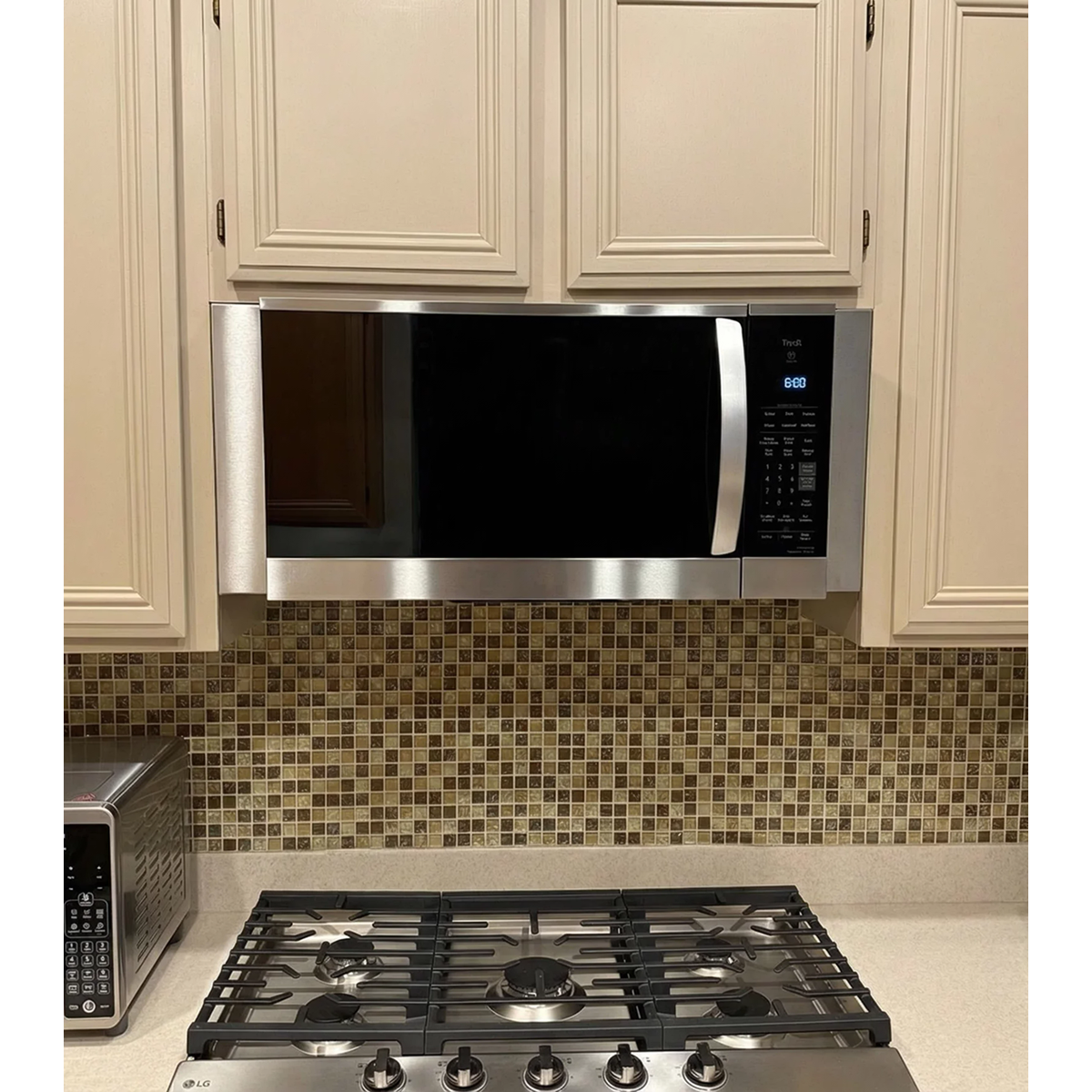 Professional over-the-range microwave installation featuring custom stainless steel filler panels that bridge the gap for built-in finish