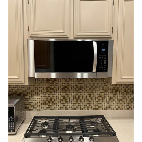Professional over-the-range microwave installation featuring custom stainless steel filler panels that bridge the gap for built-in finish